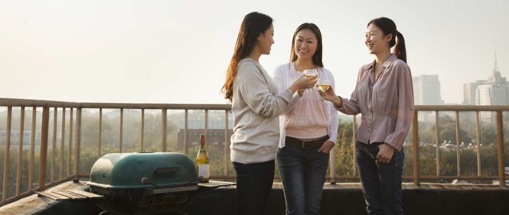 Friends drinking wine with barbecue in background