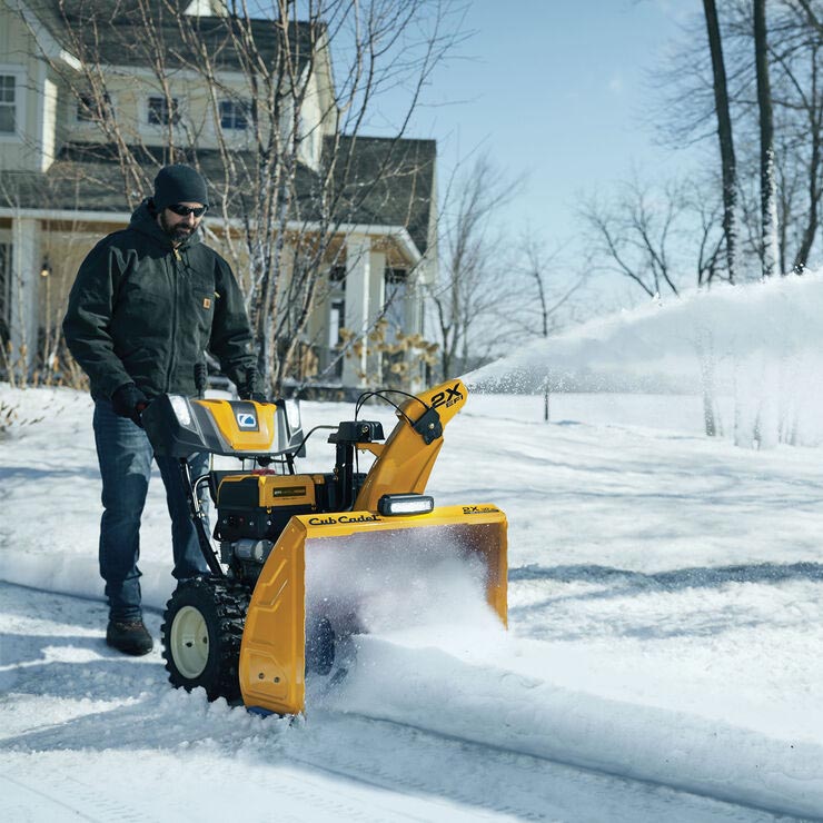 Man using snow thrower in front of home