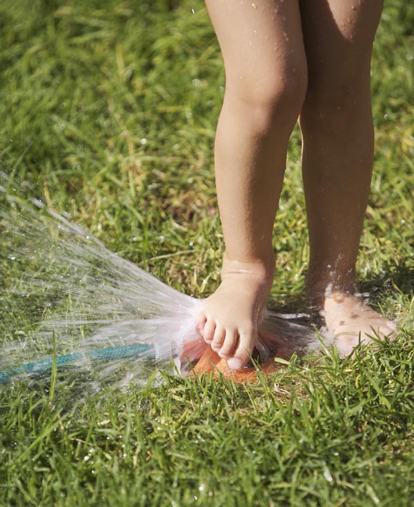 South Africa, Cape Town, girl playing with lawn sprinkler