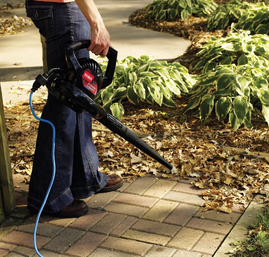 Man using leaf blower on side walk