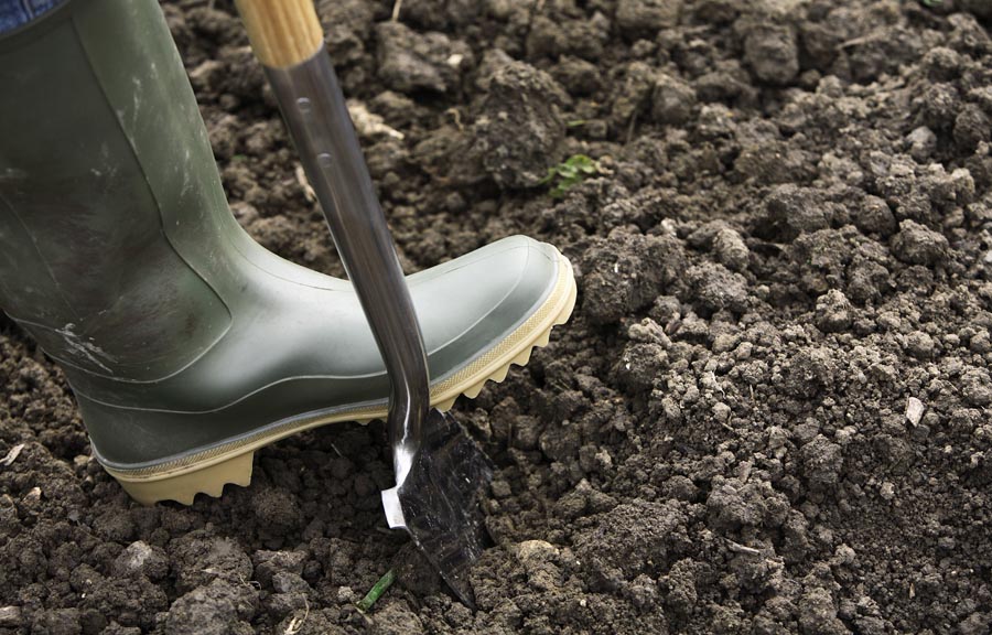 Welly boat with foot on spade in soil