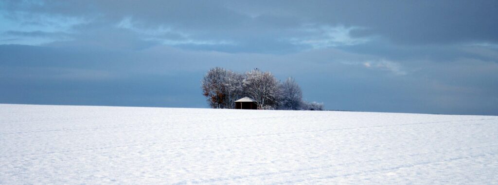 Large field of snow with small building at back