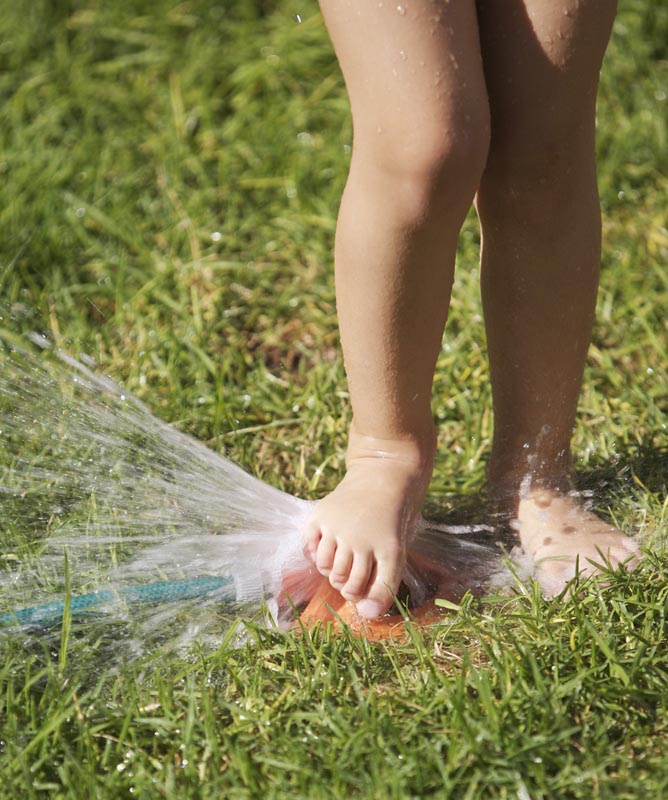 girl playing with lawn sprinkler