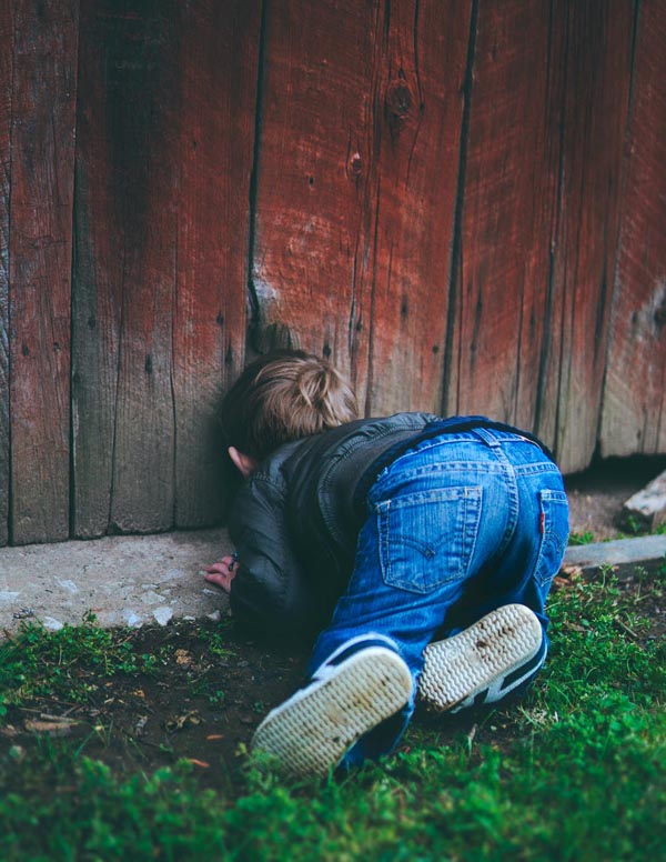 Boy looking through hole in fence