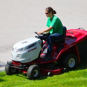 Lady on riding mower mowing lawn