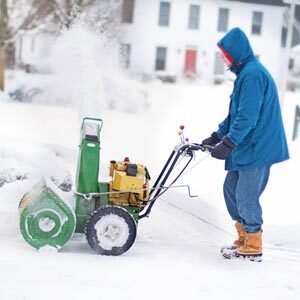 Man pushing snow blower in heavy snow