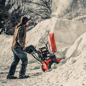 Man pushing snow blower in big snow drift