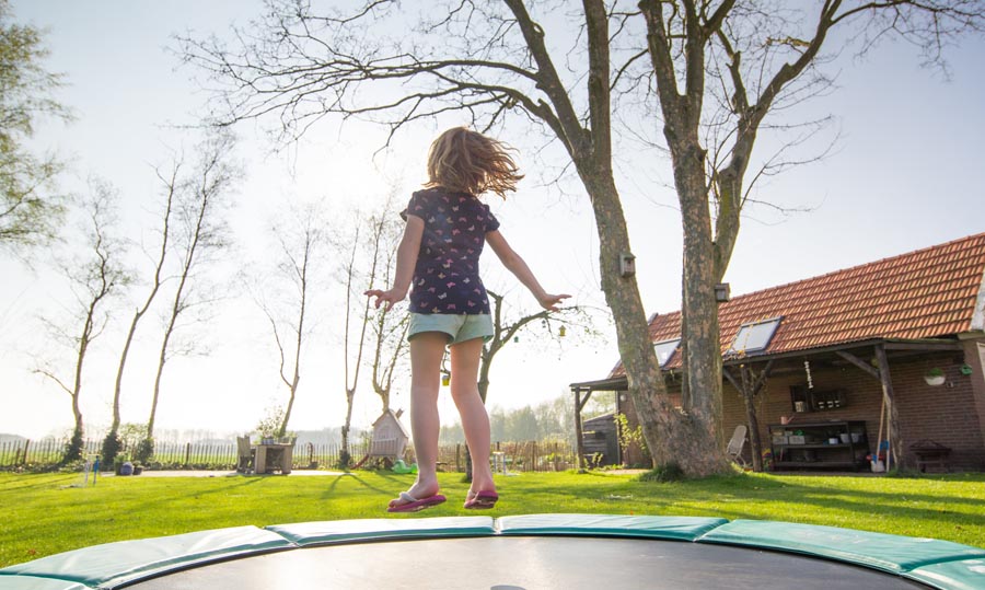 Child jumping on trampoline from behind